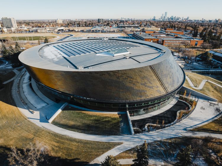 Aerial of a round, copper-tiled recreation centre with solar panels on the roof surrounded by parks and neighbourhoods