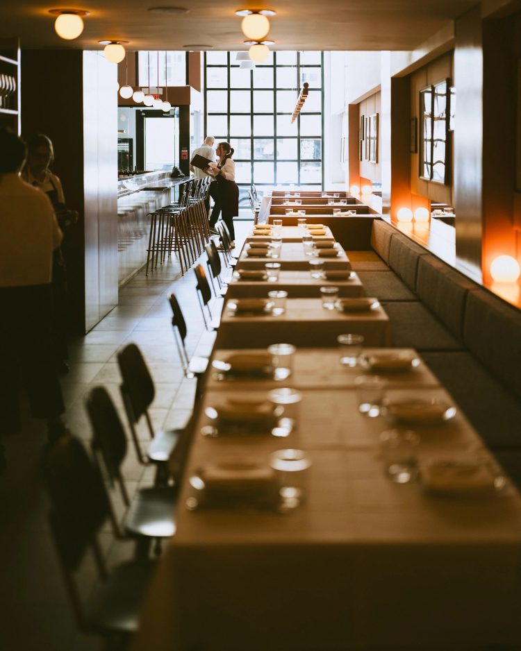 Several long tables along the wall of a bright restaurant. CR: Rita Trattoria