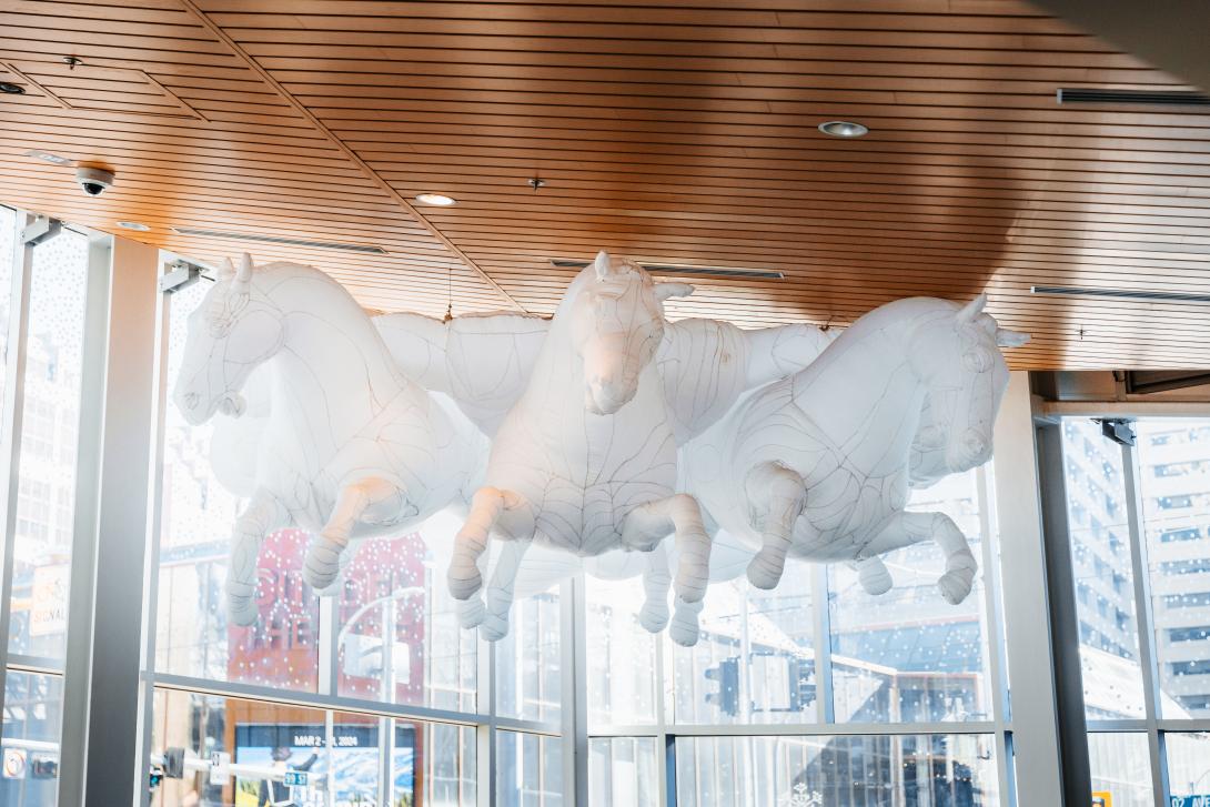 An inflated sculpture portrays three horses emerging from a cloud structure.