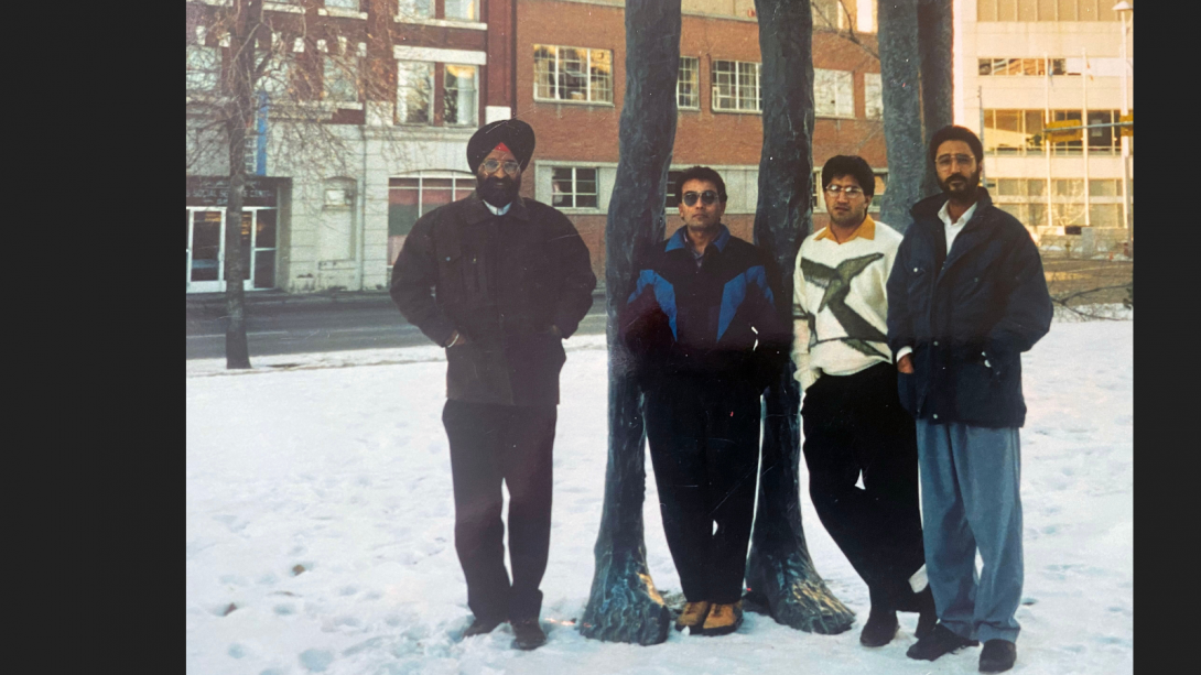 A young Mayor Sohi stands with three other men outside of the University of Alberta in the winter.